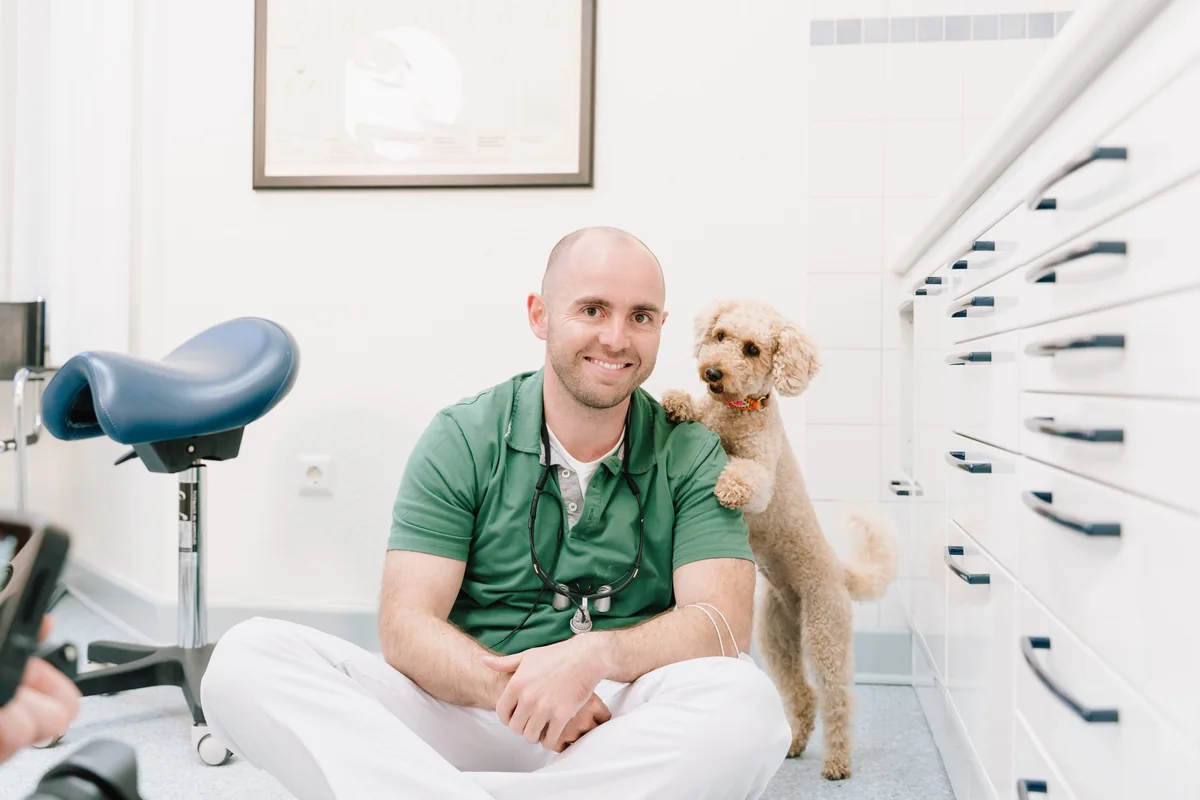 Dr. Marius Wagner sitzt mit Maja, der Therapiebegleitung der Praxis, in einem Behandlungszimmer in Husum
